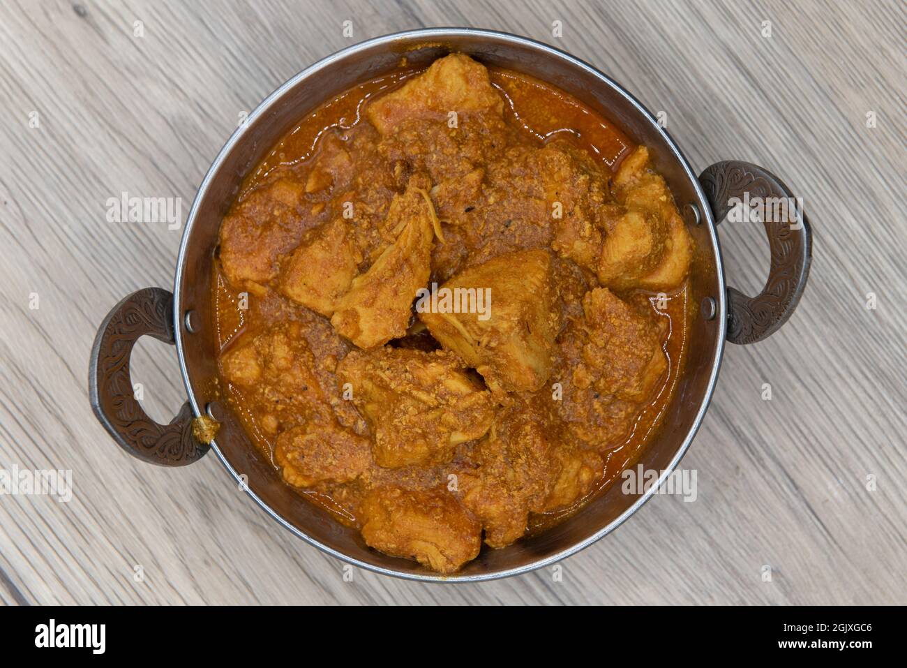 Overhead view of curry flavored chicken meat in a bowl from Indian restaurant cooked and seasoned perfectly. Stock Photo