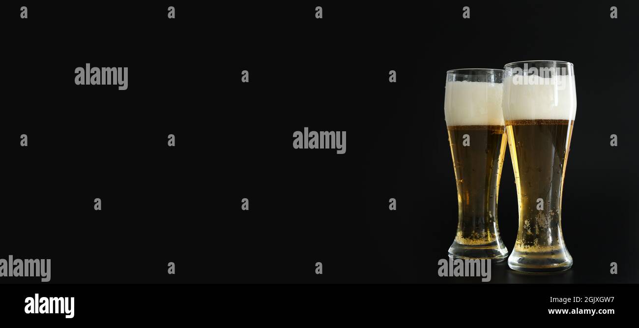 Two frosty glasses of cold golden beer with bubbles on the black background. Free space for text, copy space, banner. Drinking alcohol on party Stock Photo
