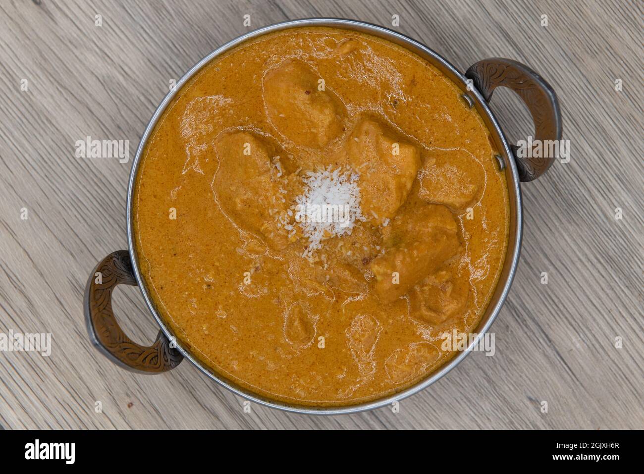 Overhead view of cocnut curry flavored chicken meat in a bowl from Indian restaurant cooked and seasoned perfectly. Stock Photo
