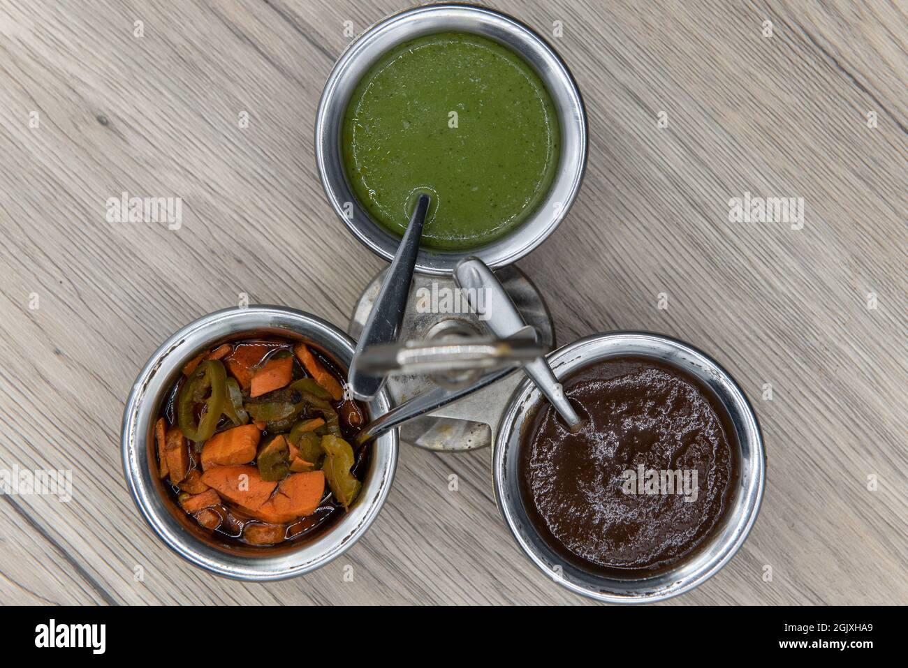 Overhead view of flavor enhancing condiments with silver serving spoon and round cannisters for easy variety choice of seasoning for your food. Stock Photo