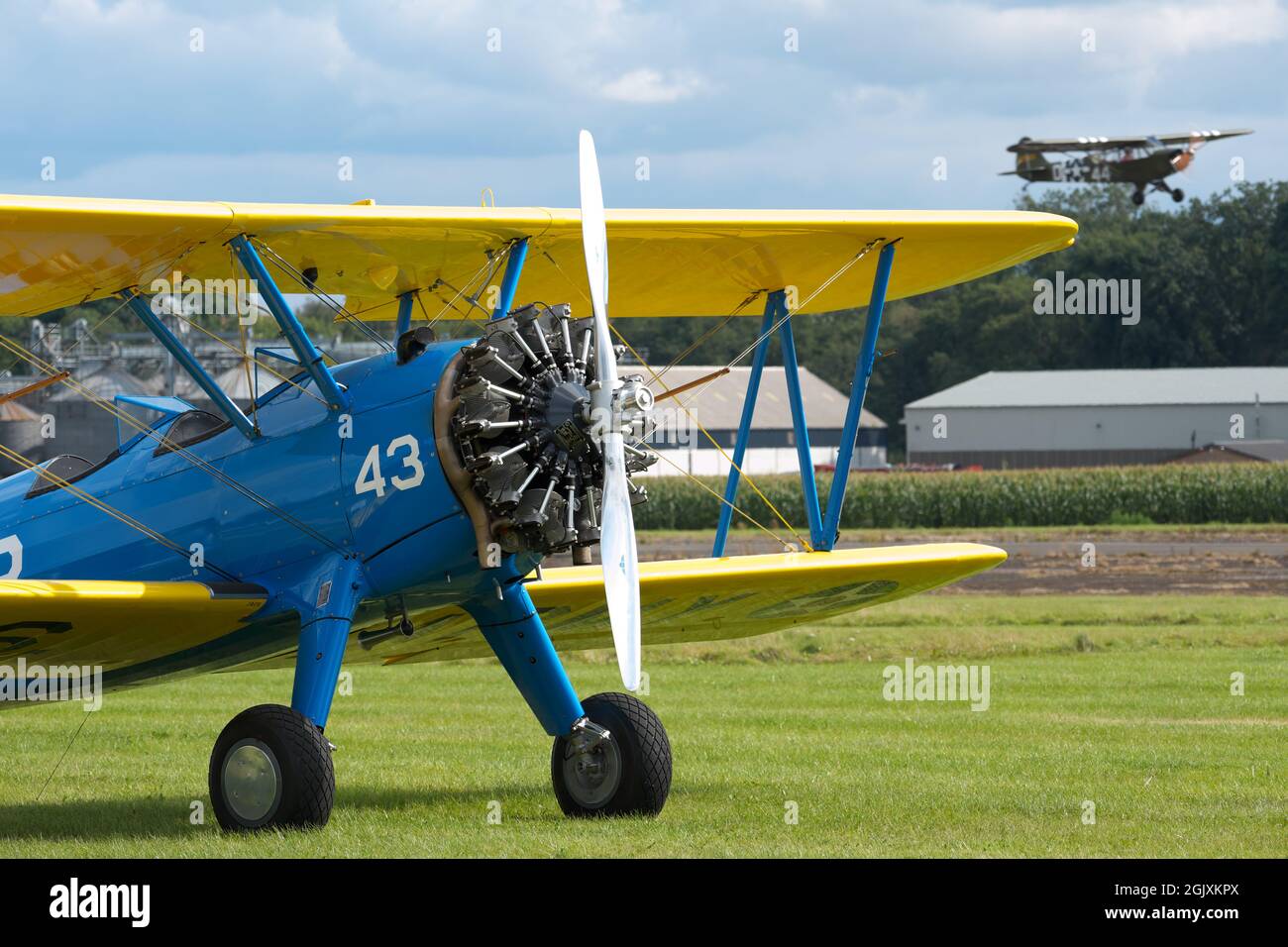 Boeing Stearman biplane training aircraft from WW2 with a vintage Piper Cub warbird flying in the background Stock Photo