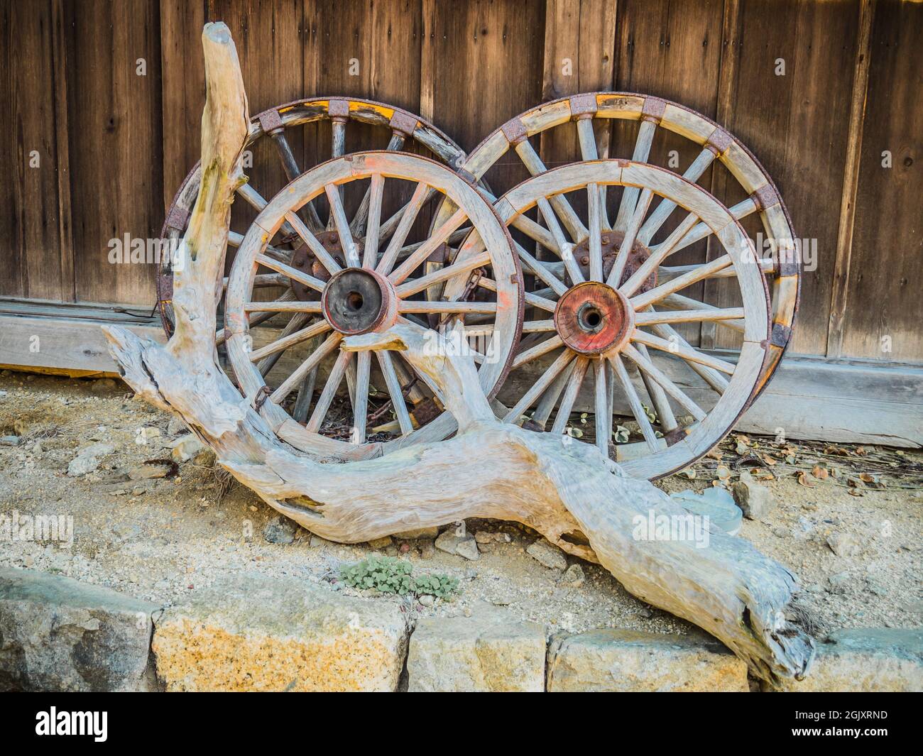 The old wooden wagon wheels and a dried wood on the side of a street