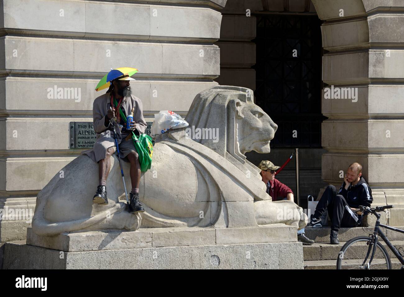 Strange guy with umbrella hat, sitting on the Left Lion Stock Photo Alamy