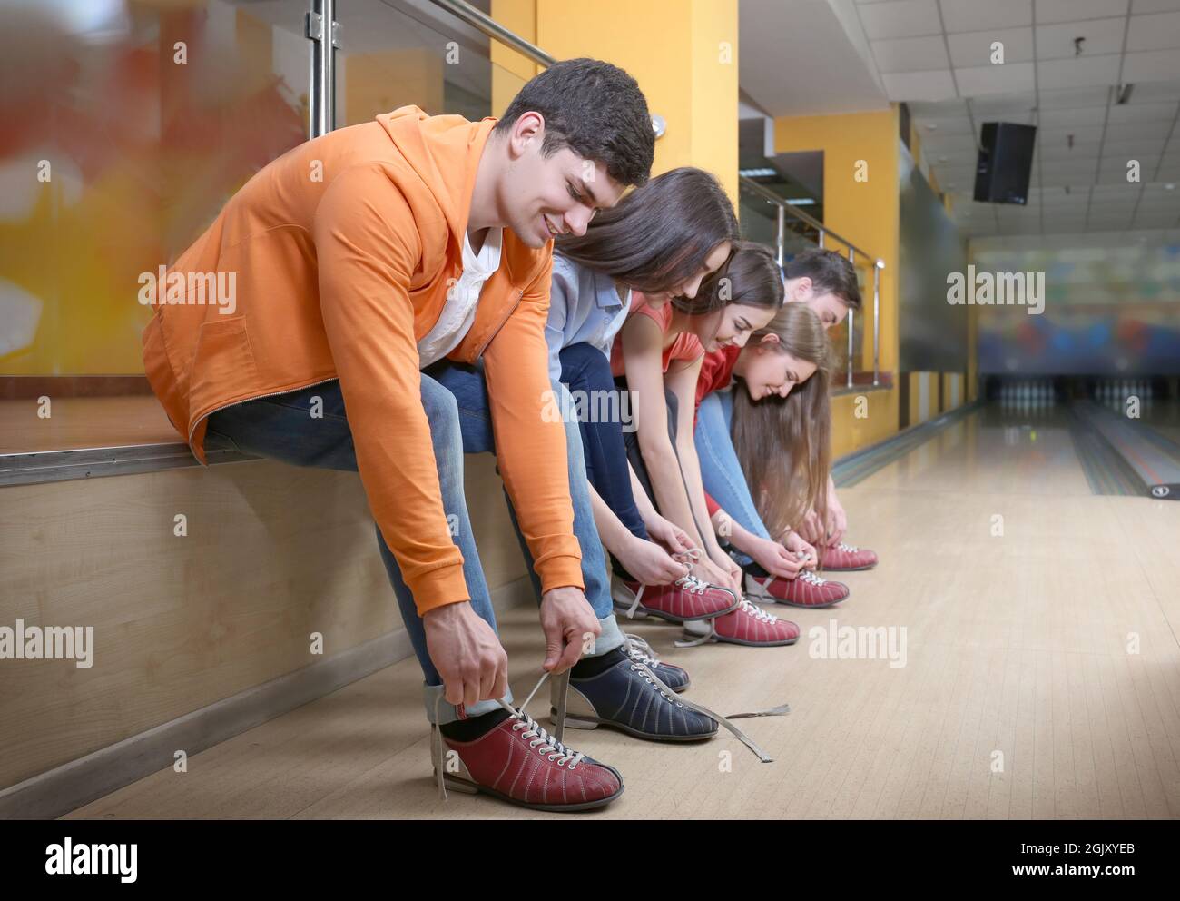 Group of young people changing their shoes in bowling club Stock Photo