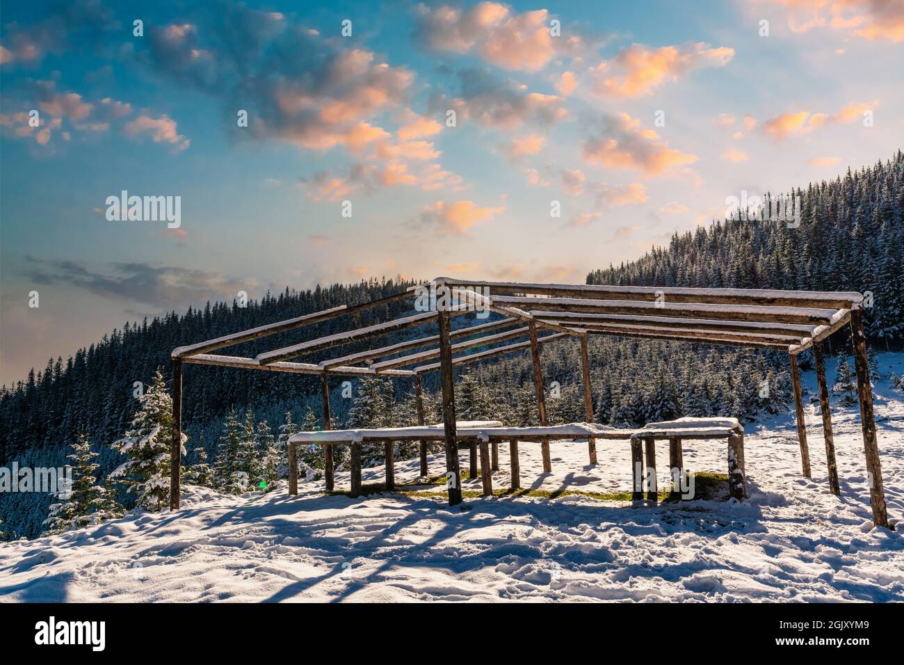 The gazebo on the top of the mountain stands in a snow-covered meadow ...