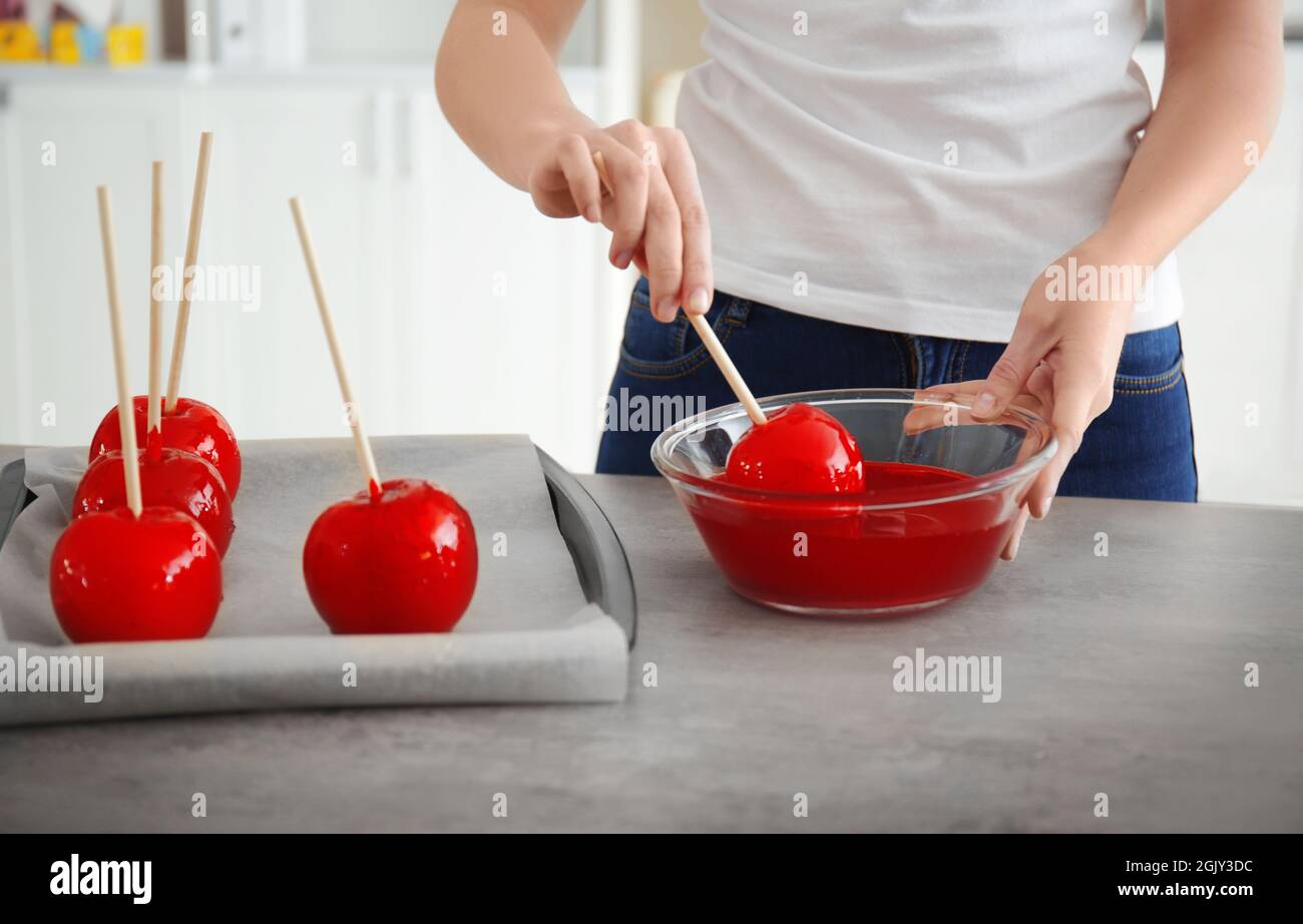 Woman dipping candy apple into glass bowl with caramel Stock Photo Alamy