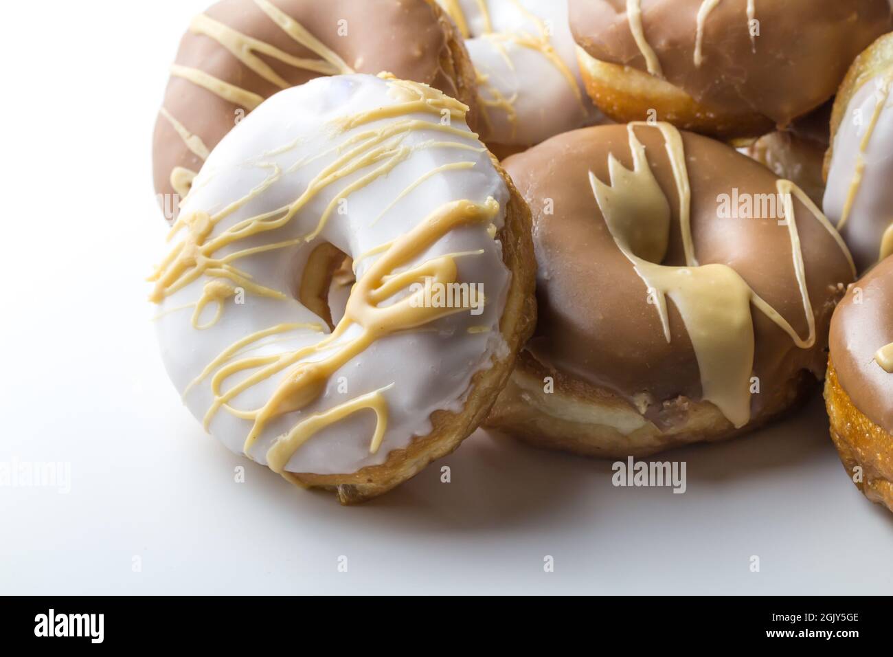 Delicious dougnuts stack with chocolate, caramel and white frosting isolated on white background with space for text Stock Photo