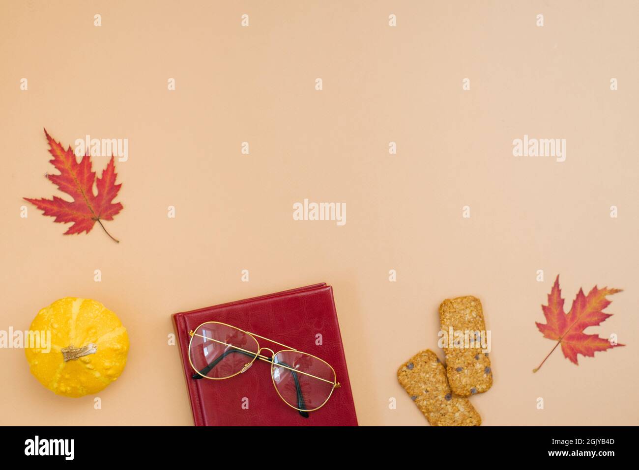 Autumn flat lay, top view of freelancer or blogger home office desk. workspace with pumpkin, leaves, cookies, notepad and glasses on a beige backgroun Stock Photo