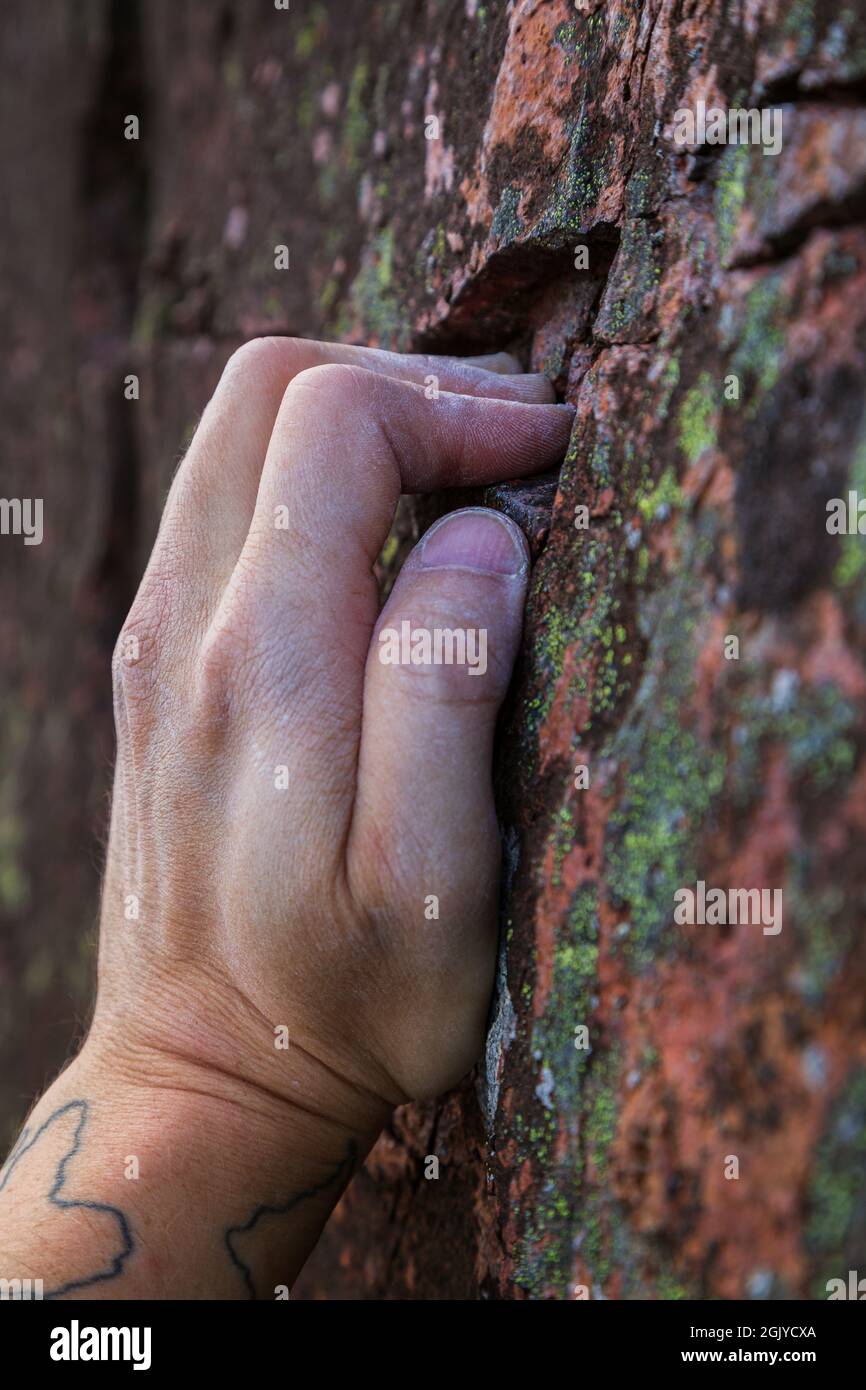 Close-up of a rock climber's chalky hand gripping a small hold on a rock. Stock Photo