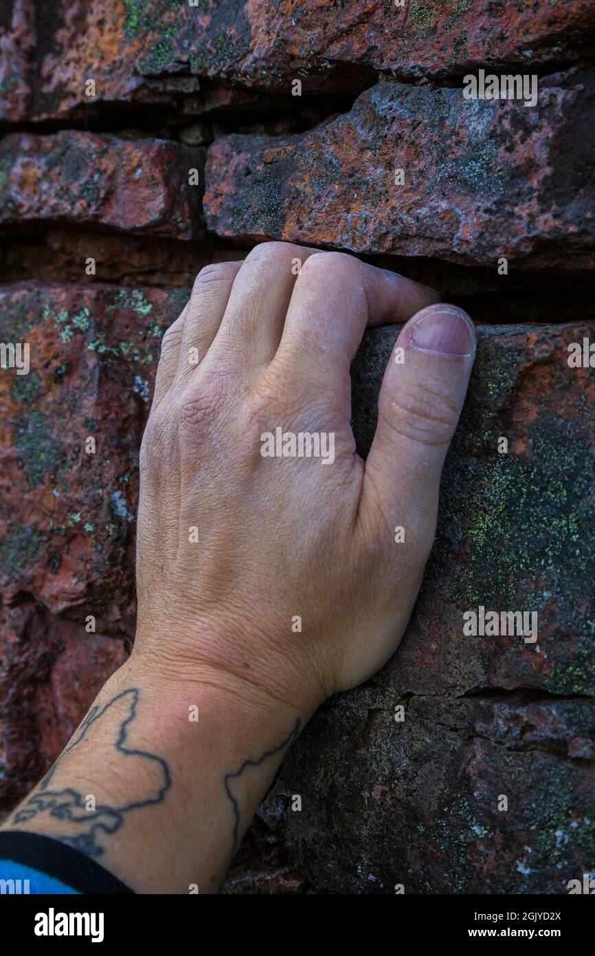 Close-up of a rock climber's chalky hand on a small crack on a rock. Stock Photo
