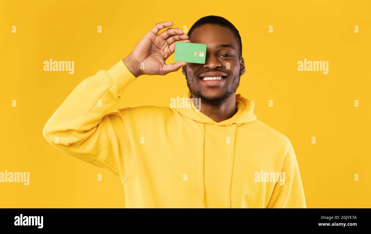 Black Guy Covering His Eye With Credit Card, Yellow Background Stock ...