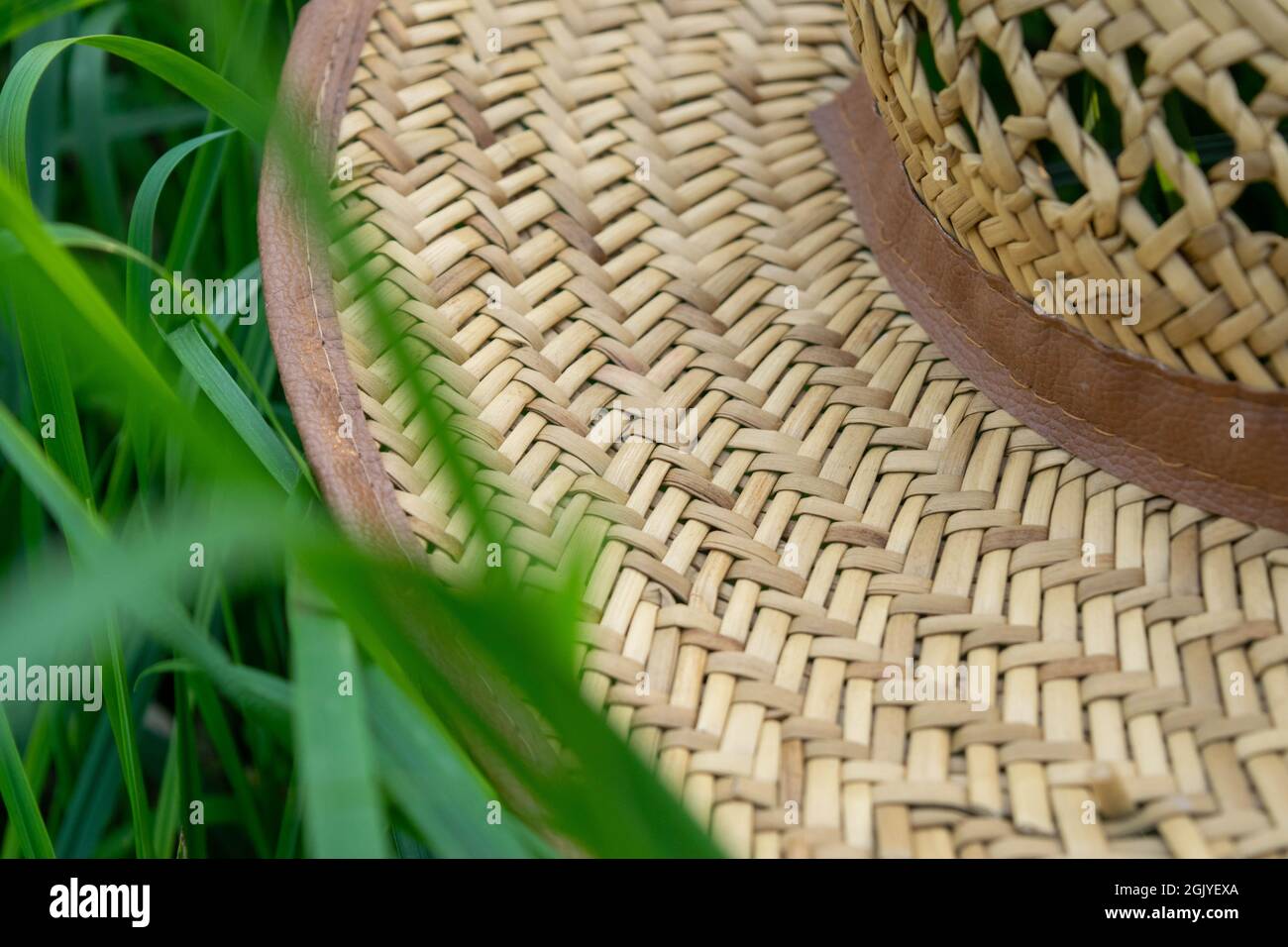 An old straw hat on the green grass, close-up, selective focus Stock Photo