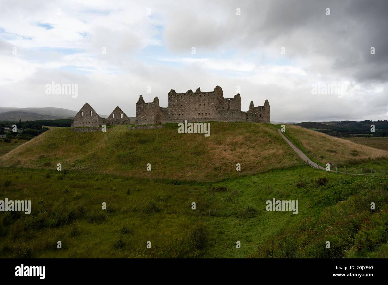 The ruins of Ruthven Barracks in the Scottish Highlands. Path leading to building which is on a hill. Blue sky and clouds, grassy area. Stock Photo