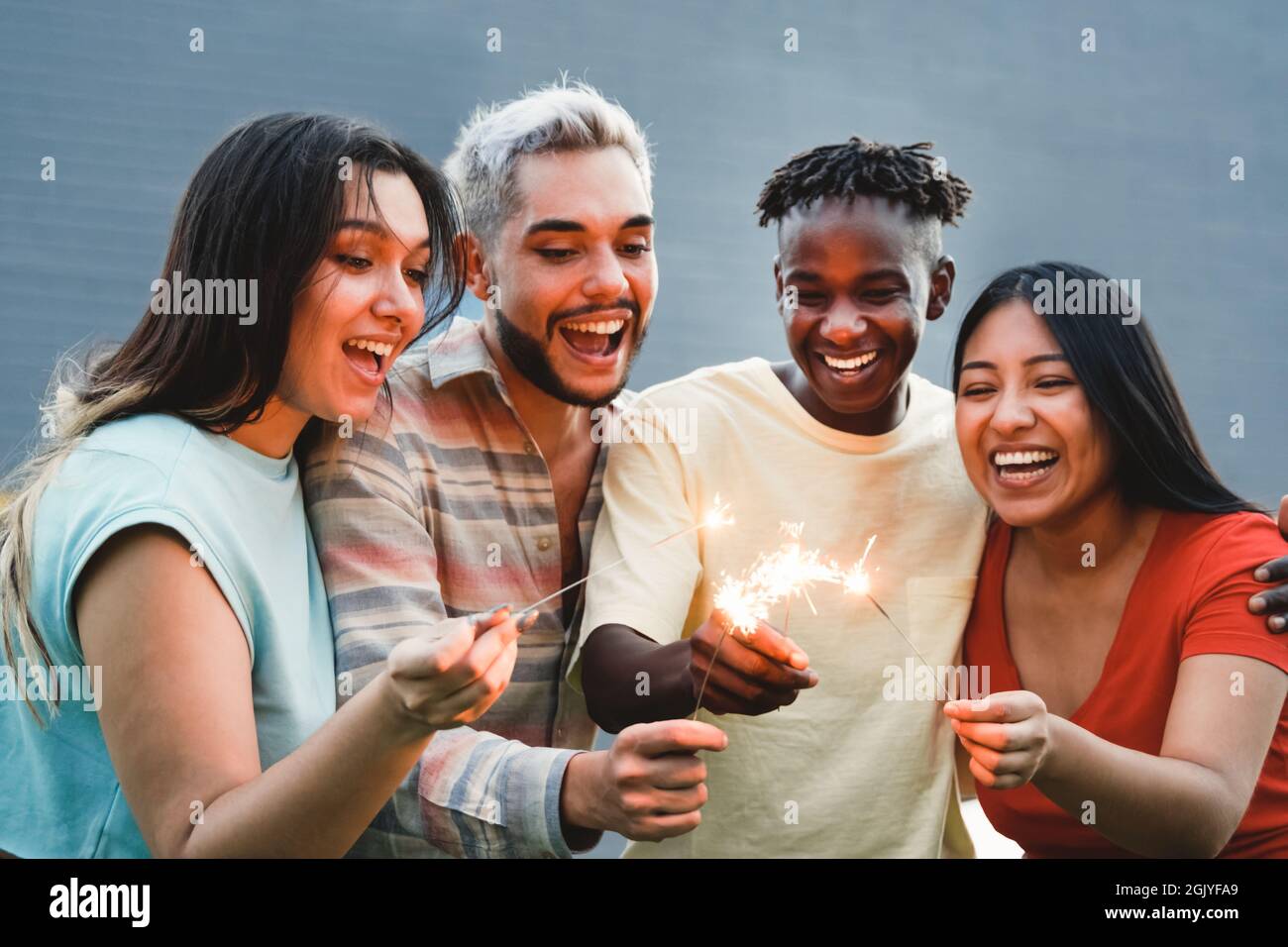 Diverse friends having fun celebrating with fireworks - Focus on right hands holding sparklers Stock Photo
