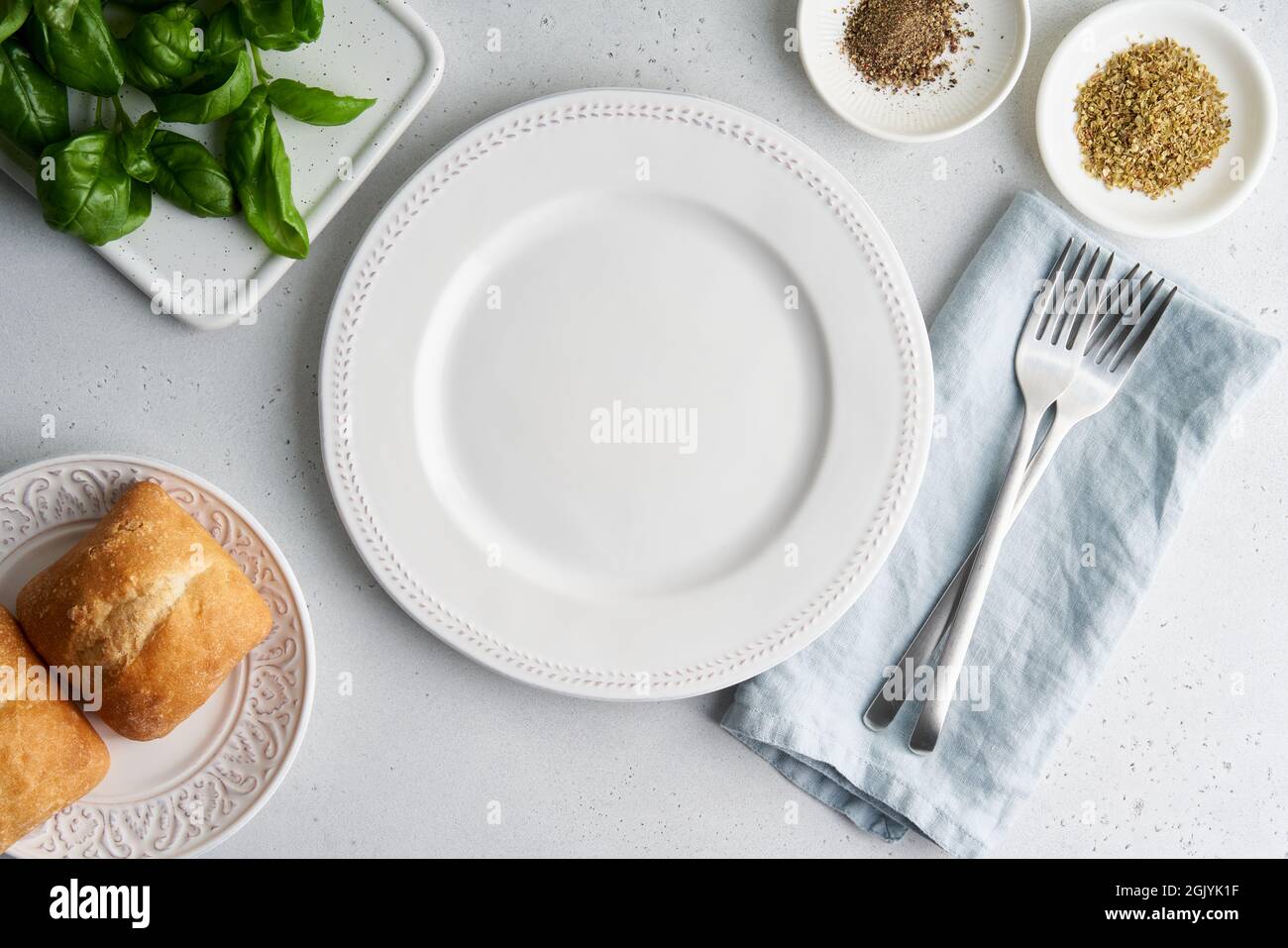 Empty white plate. Bread, lettuce, spices, tableware on light background. Top view, horizontal Stock Photo