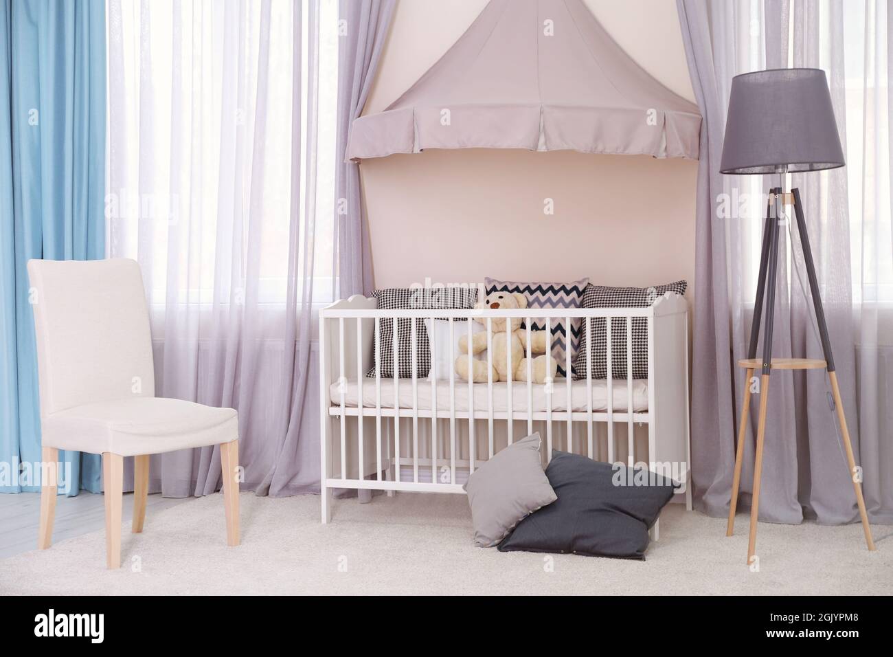 Interior of light baby room with furniture and tripod floor lamp Stock