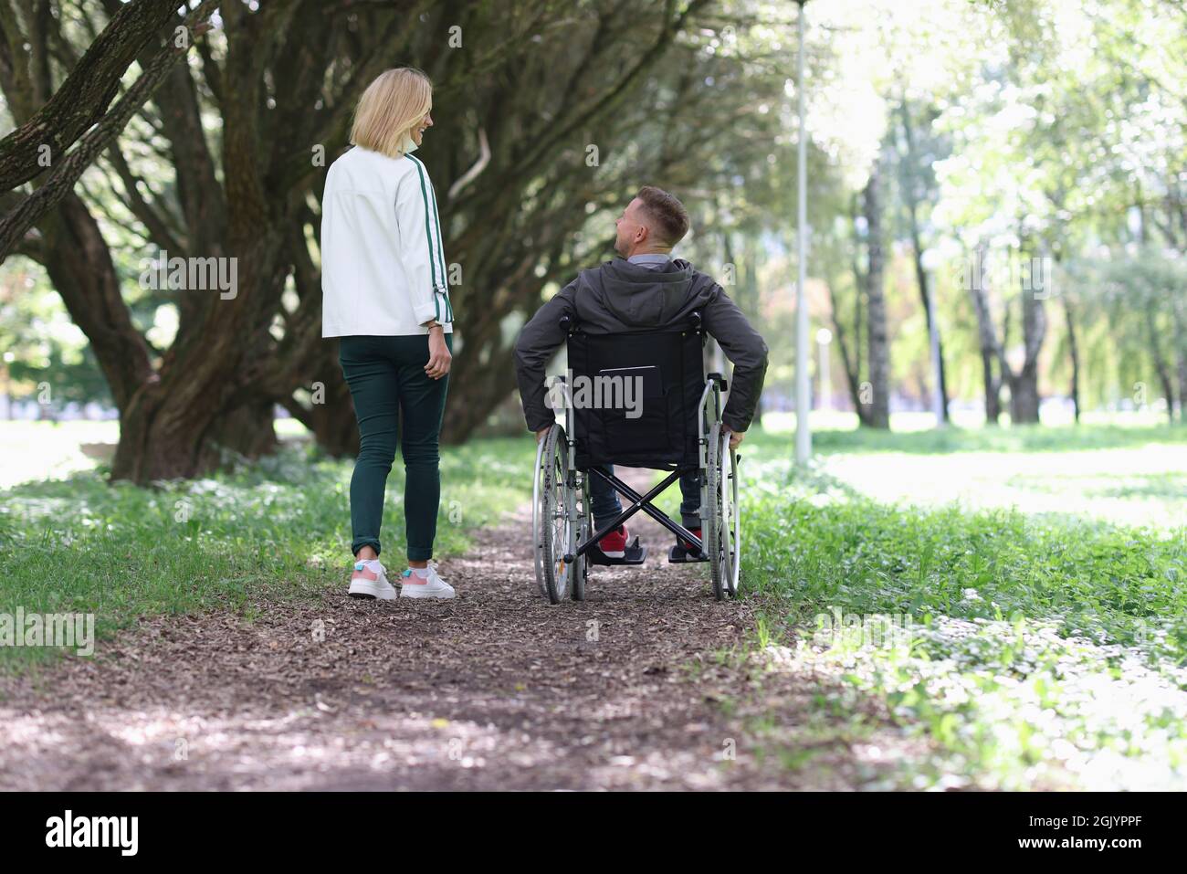 Man in wheelchair is walking in park with his girlfriend Stock Photo ...