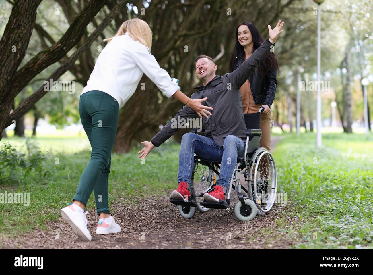 Disabled man in wheelchair walking in park with nurse and hugging his ...