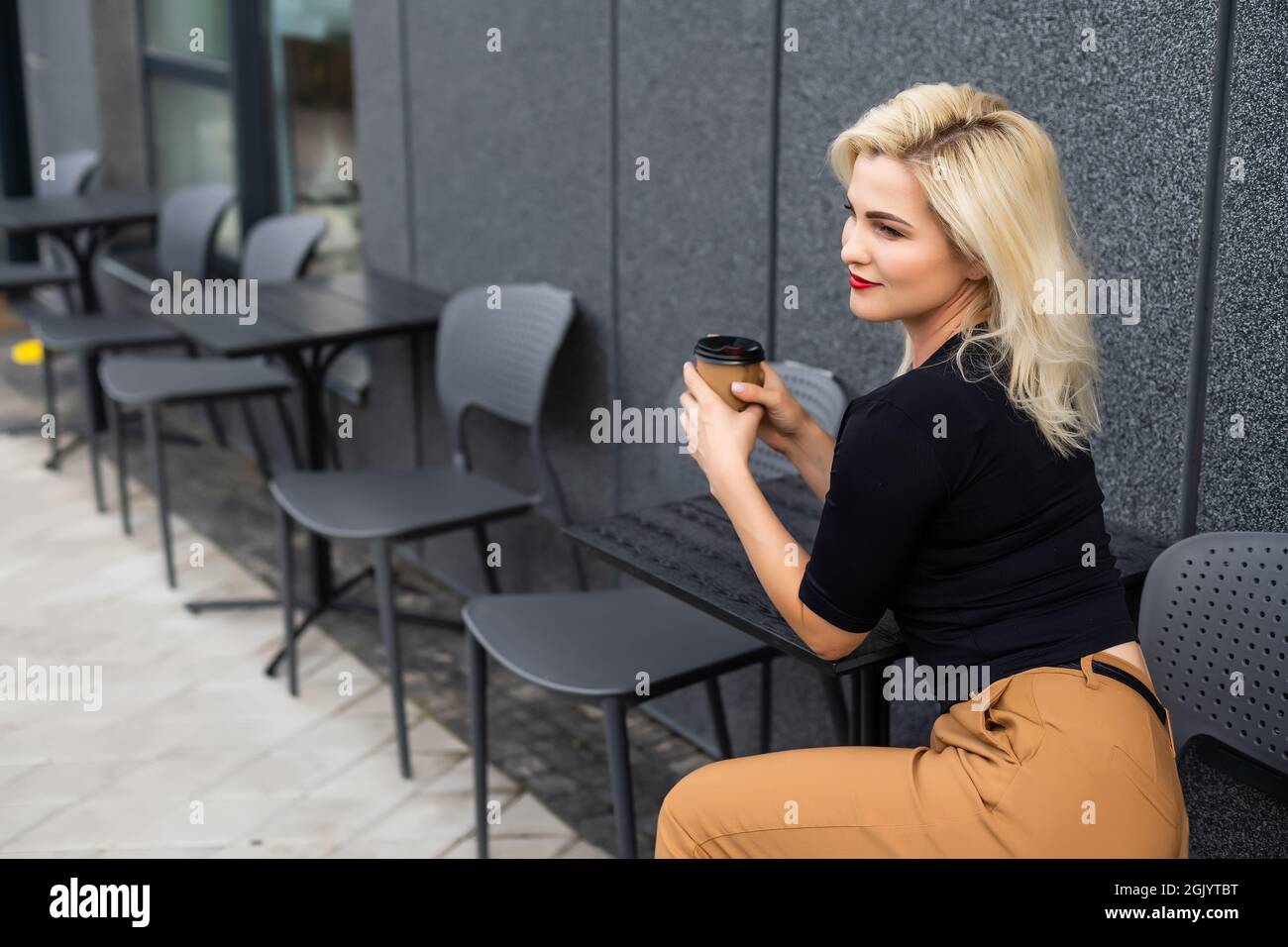 Young woman having a breakfast with coffee at the cafe terrace Stock Photo