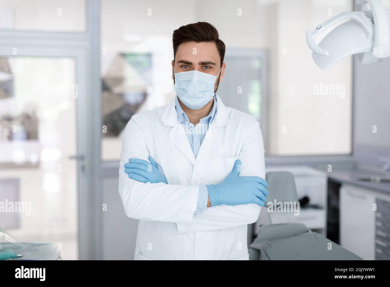 Male doctor in face mask standing at dental clinic Stock Photo