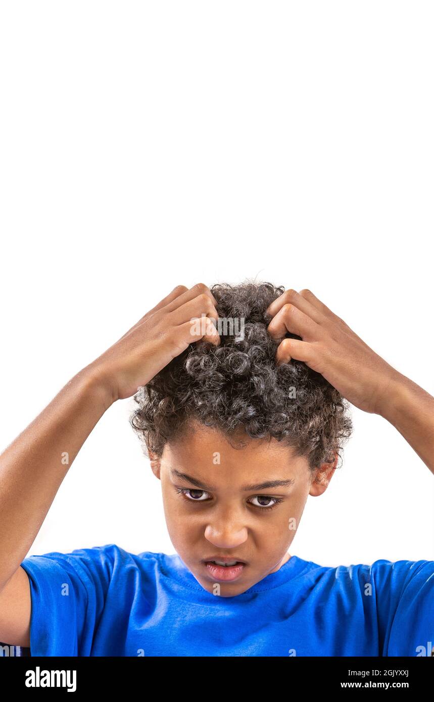 Smiling young boy scratching hair for head lice or allergies. Stock Photo