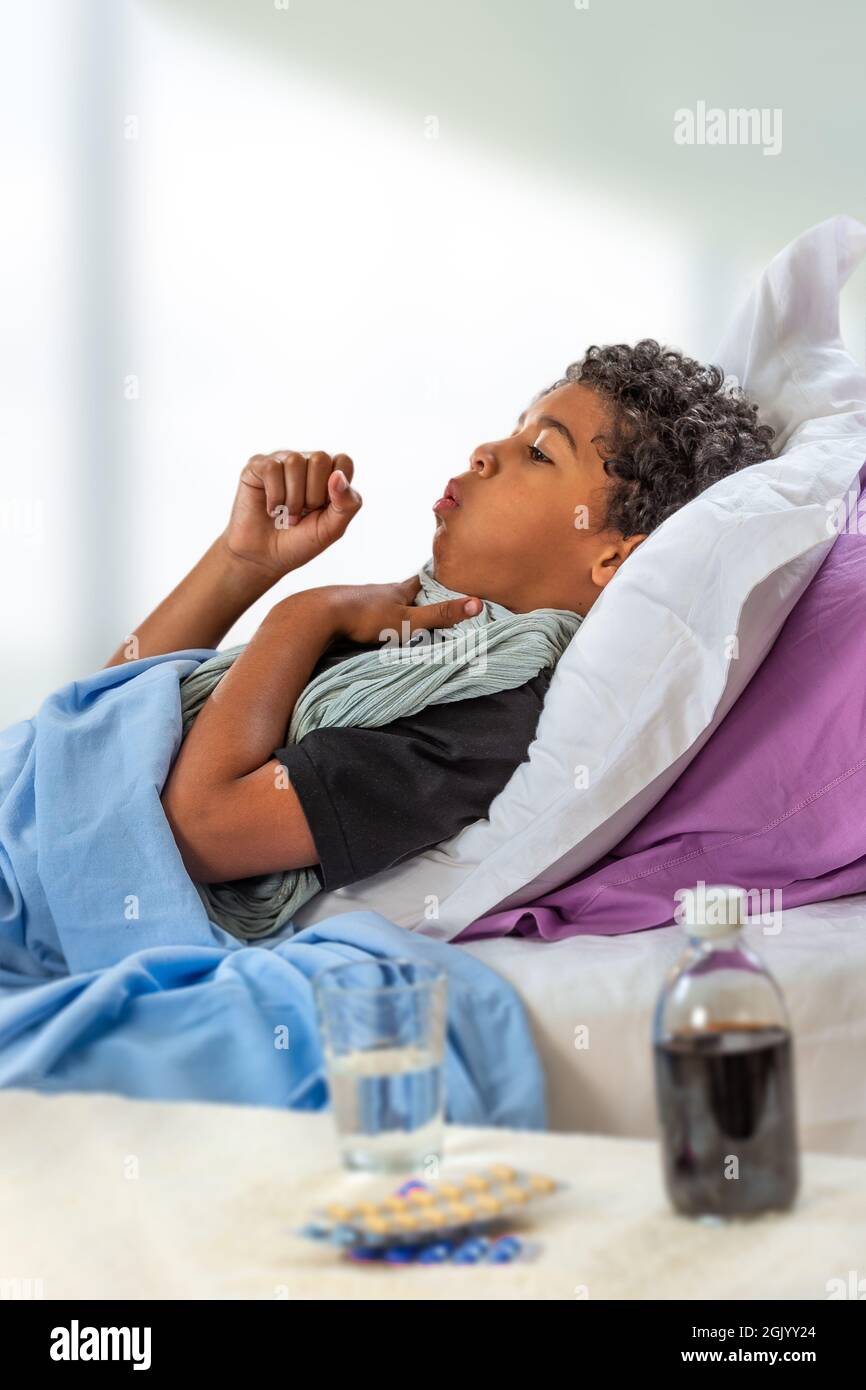 Sick child boy lying in bed with fever, resting at home. Illness kid