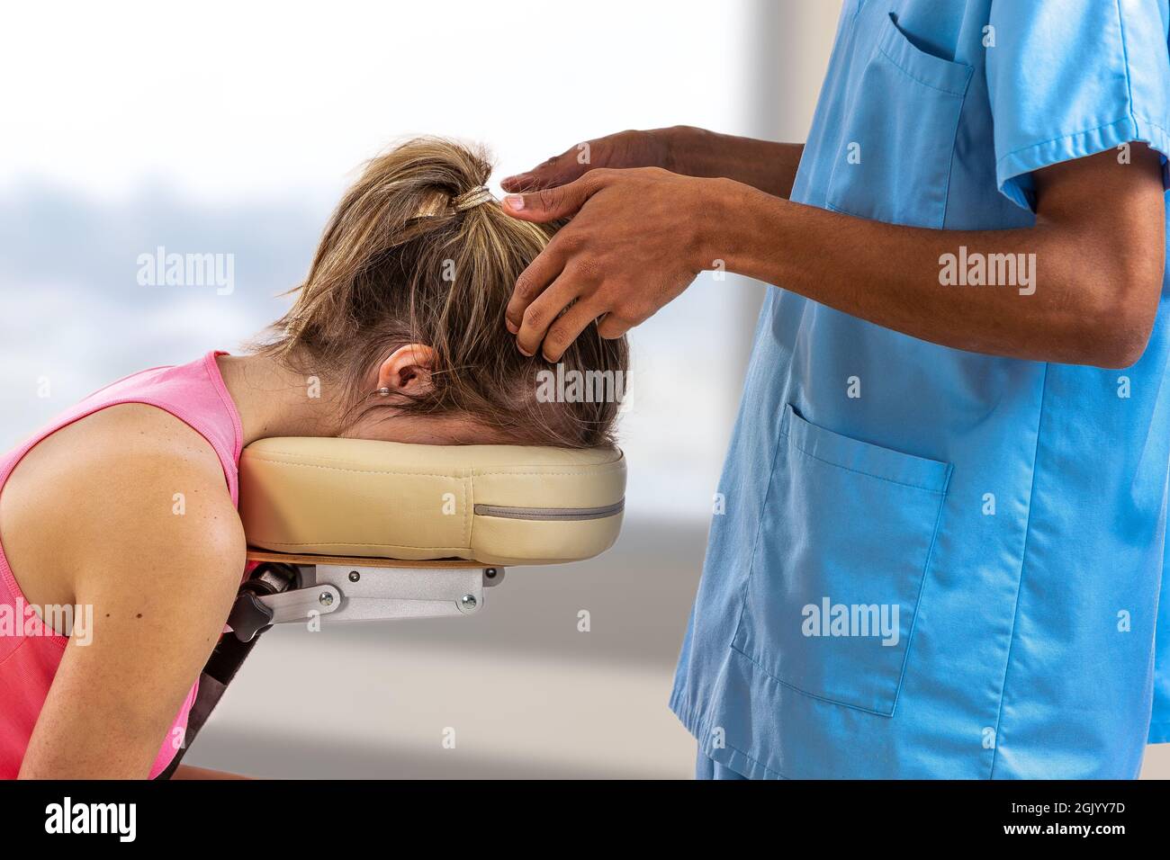 Woman lying on the back while being massaged on her head in a room Stock Photo