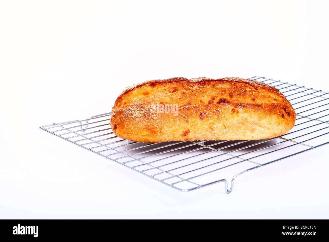 Freshly baked sourdough and cheese artisan bread laid on a wire metal cooling rack Stock Photo