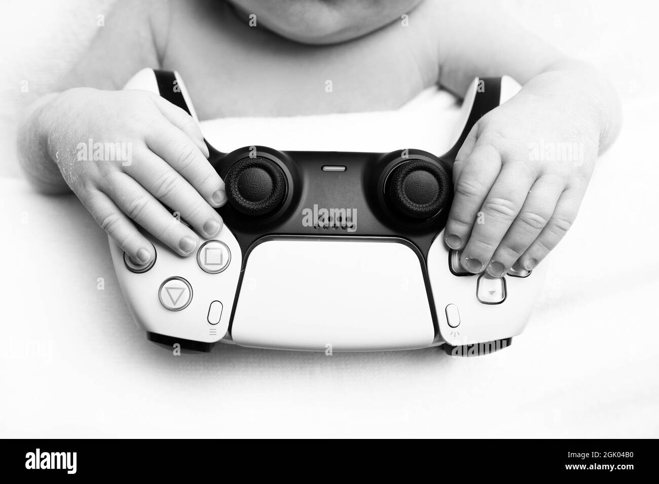 a newborn baby is holding a playstation. fingers of the hands of a newborn. black and white studio photography. Stock Photo