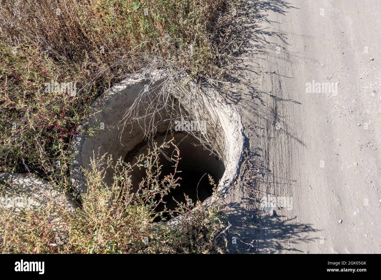 Concrete manhole near the unpaved road, Nur-sultan, Kazakhstan Stock Photo