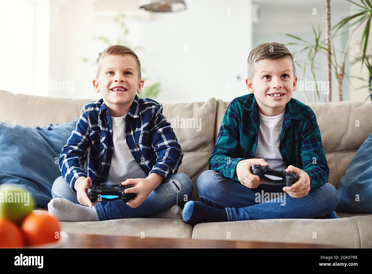 child brother friend having fun playing console laughing happy kid Stock Photo