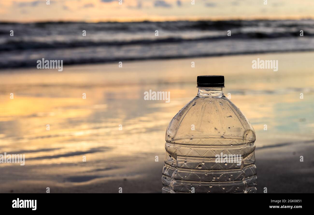 An empty water bottle on a sea beach near the ocean in the golden hour close up Stock Photo Alamy