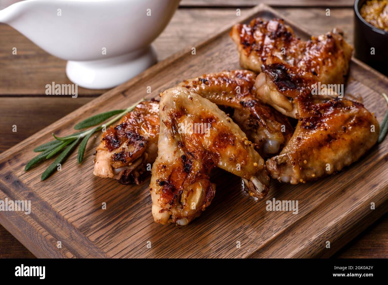 Grilled spicy chicken wings on a dark background with spices and herbs
