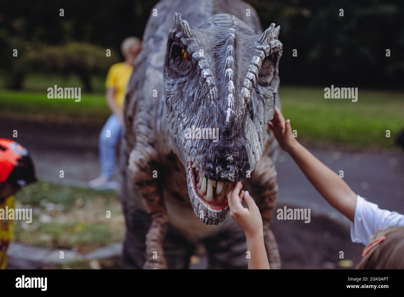 Bucharest, Romania - August 29, 2021: A man costumed as a carnivorous dinosaur walks between people and let’s them pet him during an outdoors event in Stock Photo
