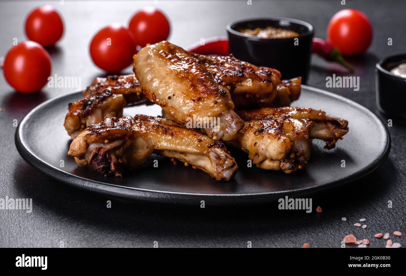 Grilled spicy chicken wings on a dark background with spices and herbs
