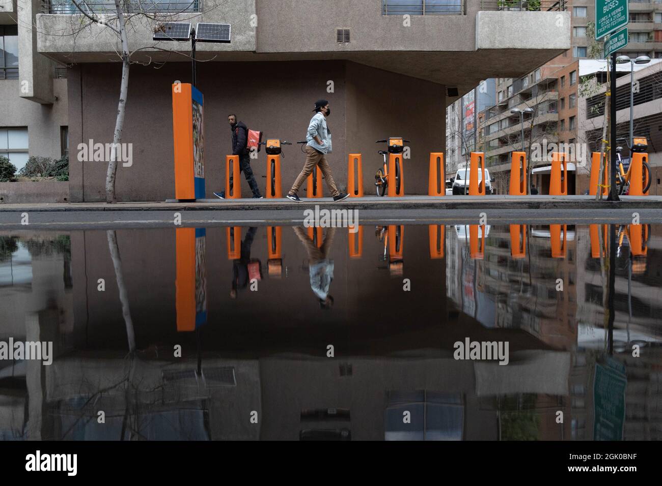 Santiago, Metropolitana, Chile. 12th Sep, 2021. Two people walking through the center of Santiago are reflected in a pool of water, after a rain at night in Santiago, Chile. (Credit Image: © Matias Basualdo/ZUMA Press Wire) Credit: ZUMA Press, Inc./Alamy Live News Stock Photo