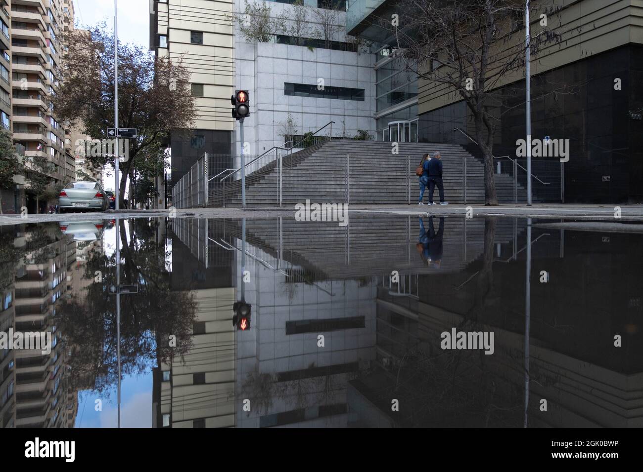 Santiago, Metropolitana, Chile. 12th Sep, 2021. A couple walking through the center of Santiago is reflected in a pool of water, after a rain at night in Santiago, Chile. (Credit Image: © Matias Basualdo/ZUMA Press Wire) Credit: ZUMA Press, Inc./Alamy Live News Stock Photo