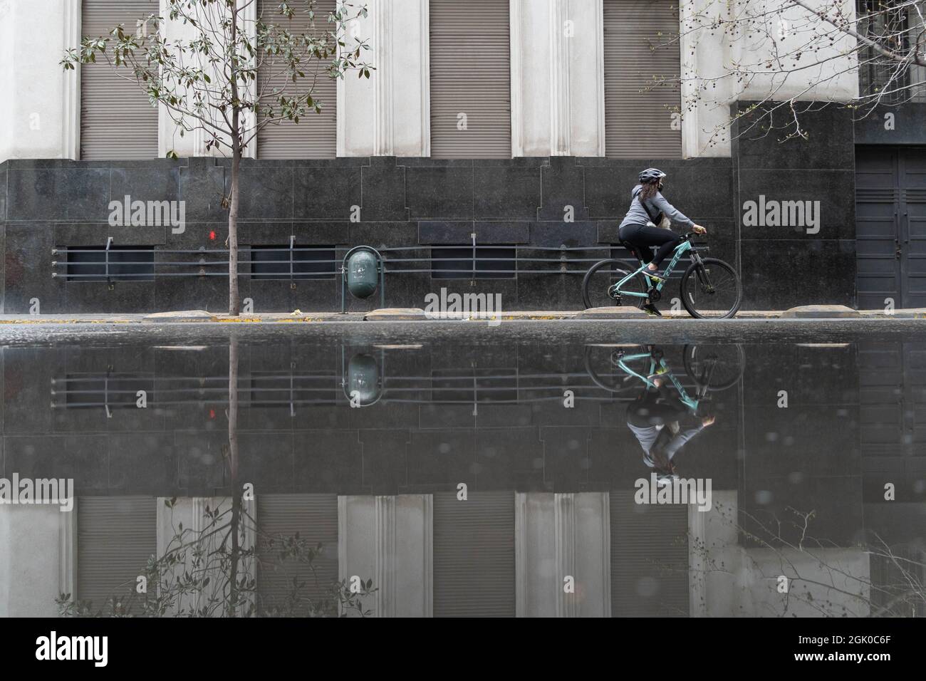 Santiago, Metropolitana, Chile. 12th Sep, 2021. A woman riding a bicycle is reflected in a pool of water, after a rain at night in Santiago, Chile. (Credit Image: © Matias Basualdo/ZUMA Press Wire) Credit: ZUMA Press, Inc./Alamy Live News Stock Photo
