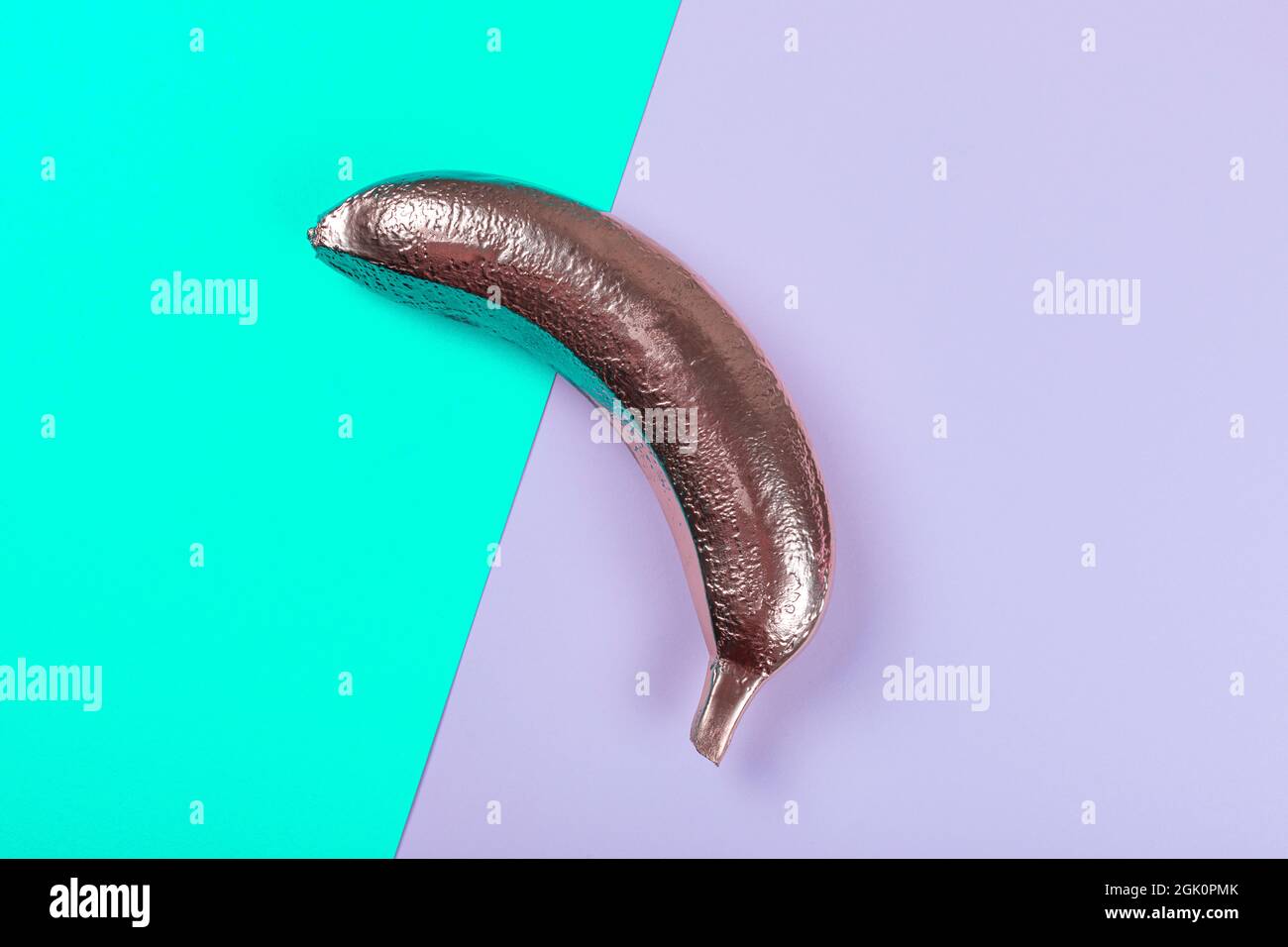 Golden banana on a pink and mint colored background. A modern creative concept. Festive or summer concept. Flat lay. Stock Photo