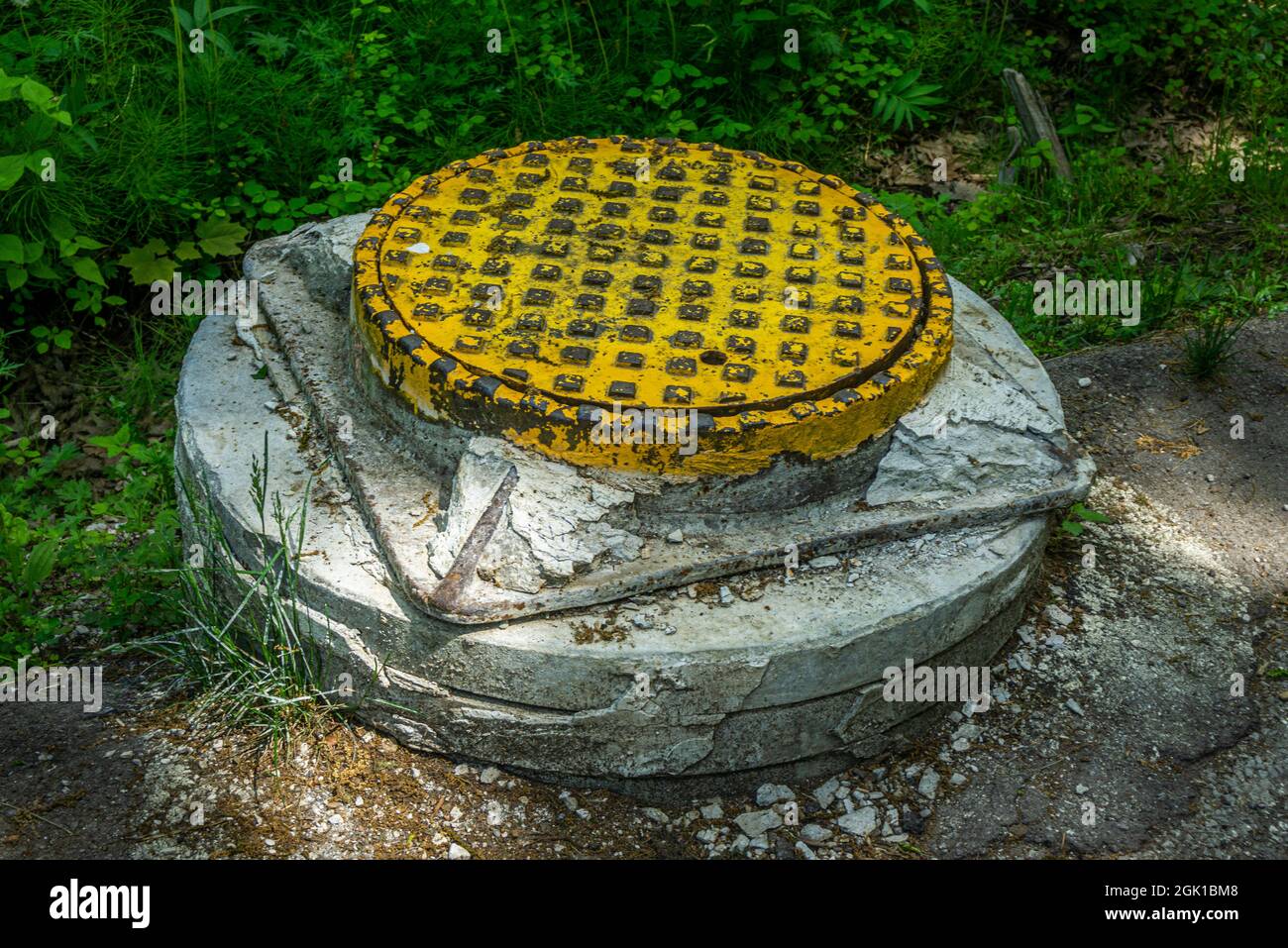 Yellow sewer cast-iron manhole cover on concrete base. Sewage drainage system Stock Photo