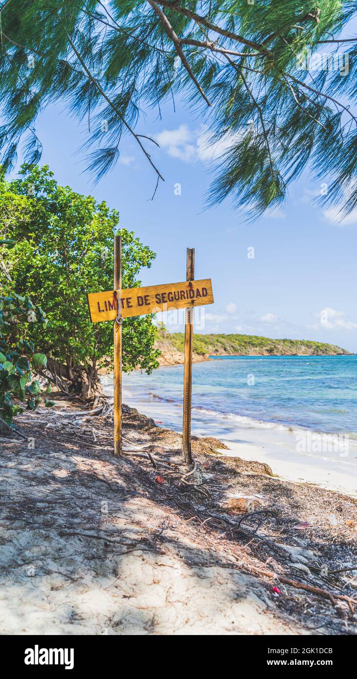 Warning sign at edge of beach against blue sky Stock Photo
