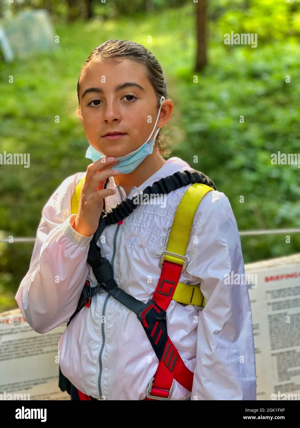 A vertical shot of a young Caucasian girl with a zip line's sportswear and mask looking at the camera Stock Photo