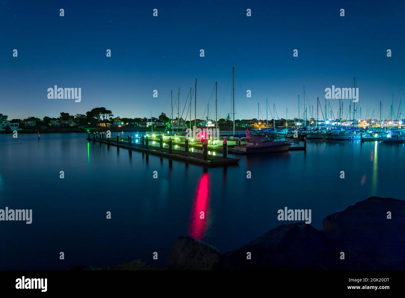 Long exposure of coastal harbour at night with boat lights reflecting