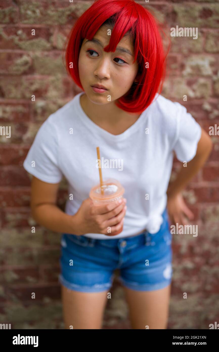 Teenage Cosplay Actress Standing in Front of Brick Wall | Asian Girl with Red Wig Stock Photo