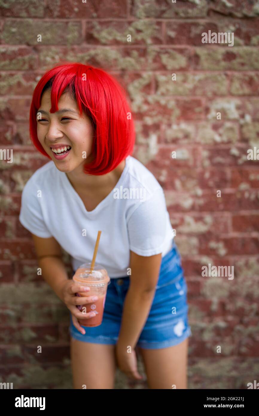 Teenage Cosplay Actress Standing in Front of Brick Wall | Asian Girl with Red Wig Stock Photo