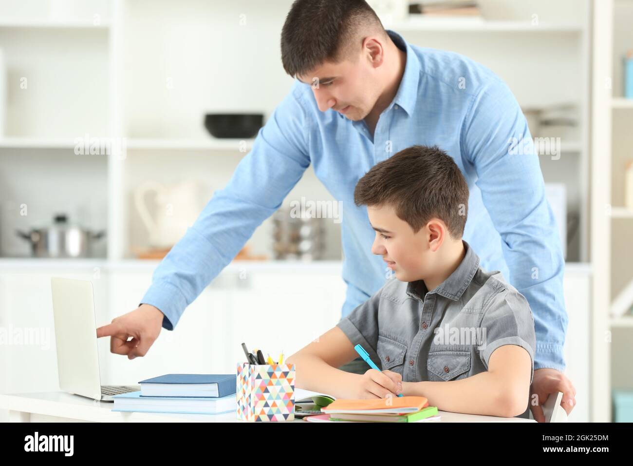 Father and son doing homework together indoors Stock Photo Alamy