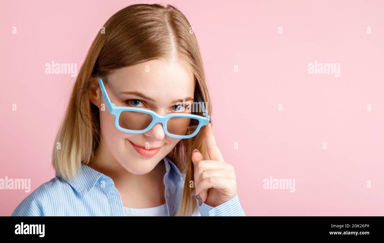 Young woman in cinema glasses for watching 3d movie in cinema. Smiling teenager girl portrait movie viewer in glasses isolated over pink color Stock Photo