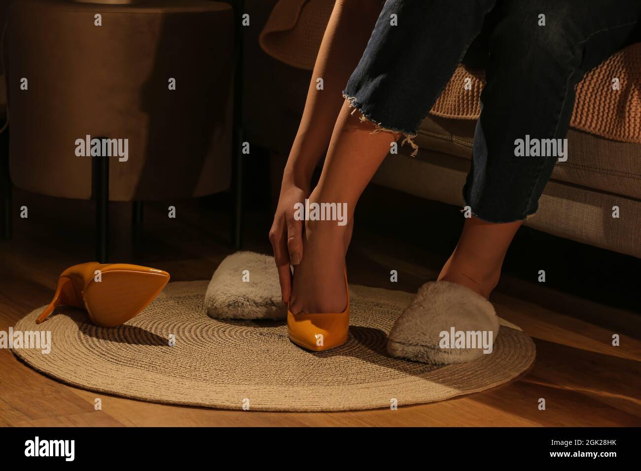Woman putting on warm slippers at home after work day, closeup Stock Photo