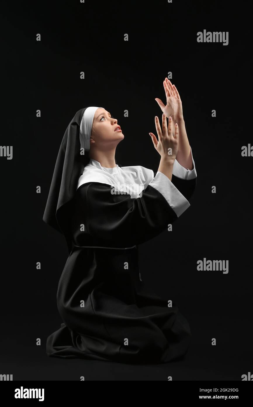 Young praying nun on dark background Stock Photo