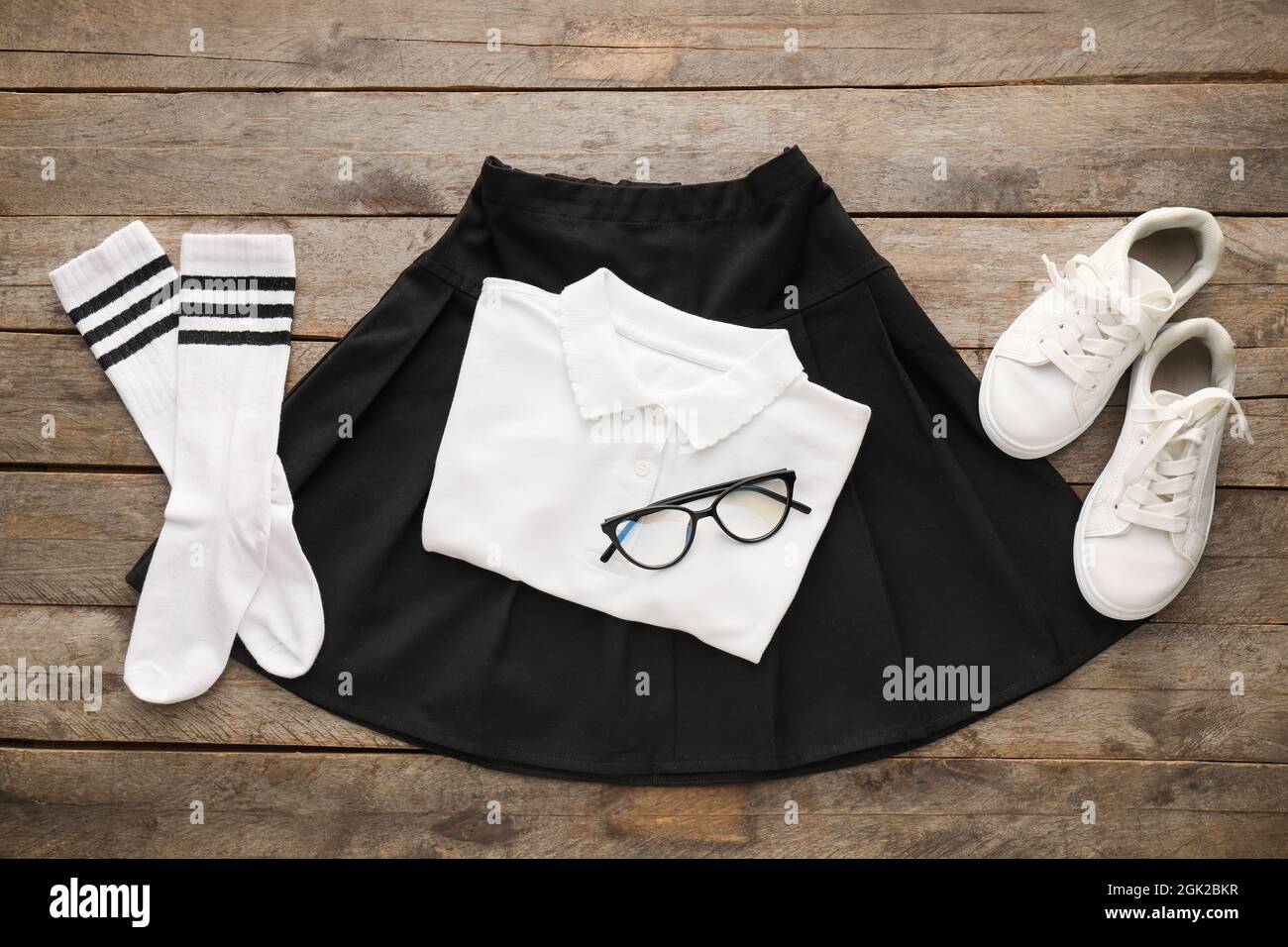 Stylish school uniform, eyeglasses and shoes on wooden background Stock Photo